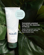 Person using Saalt squeeze bottle to rinse a menstrual disc in a travel setting.
