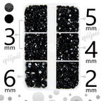 Hand holding tweezers applying black resin gems to nail art