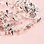 Assorted sizes of mini punk nail charms displayed next to professional manicure tools