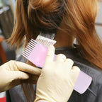Squeezable pink hair dye bottle brush being gripped for product distribution.