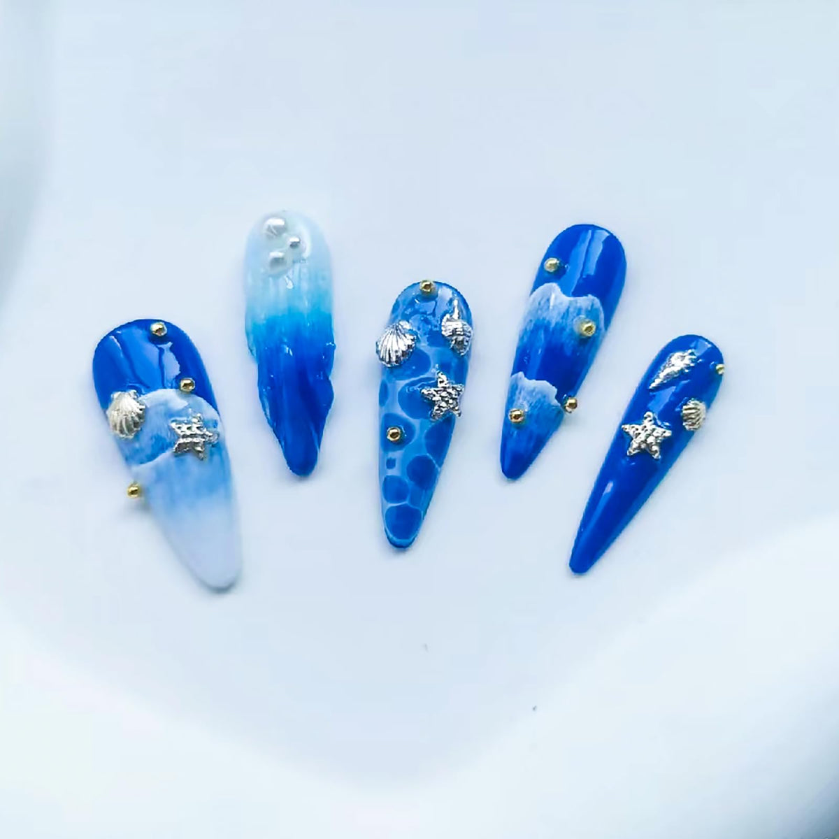Two boxes of ONEUPIN beach theme nail rhinestones and silver alloy rivets for salon quality styling.