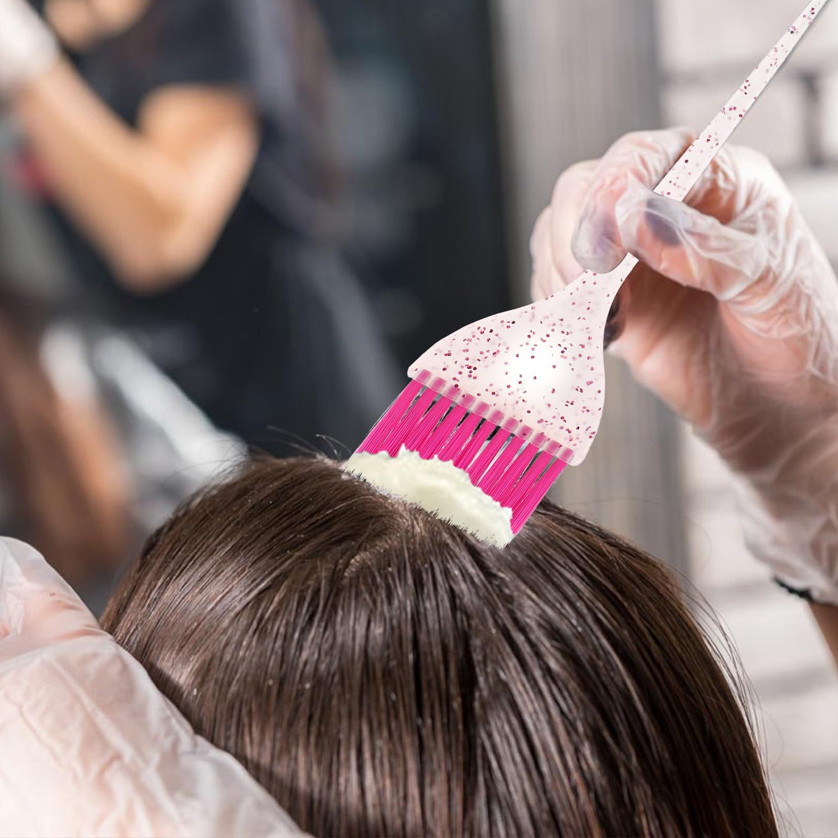 Stylist using professional glitter hair color brush for highlighting.