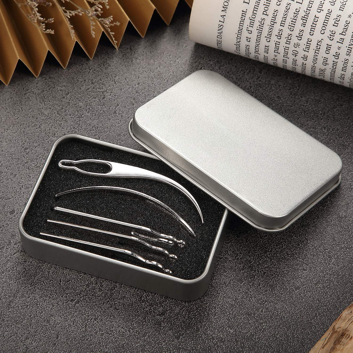 Hand holding a silver interlocking needle demonstrating hair tool dimensions