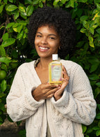 Organic plant-based vanilla body oil being applied as a lightweight hair treatment.