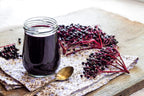 Whole dried black elderberries spilled next to the original packaging