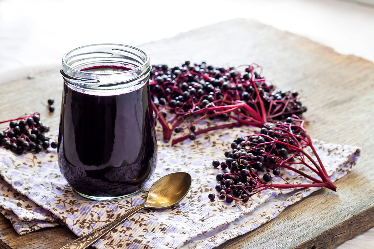 Whole dried black elderberries spilled next to the original packaging