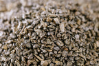 Brewed cup of organic gunpowder green tea with loose leaves