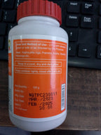 Close up view of the fine brown Ayurvedic Triphala powder next to its original Patanjali packaging.